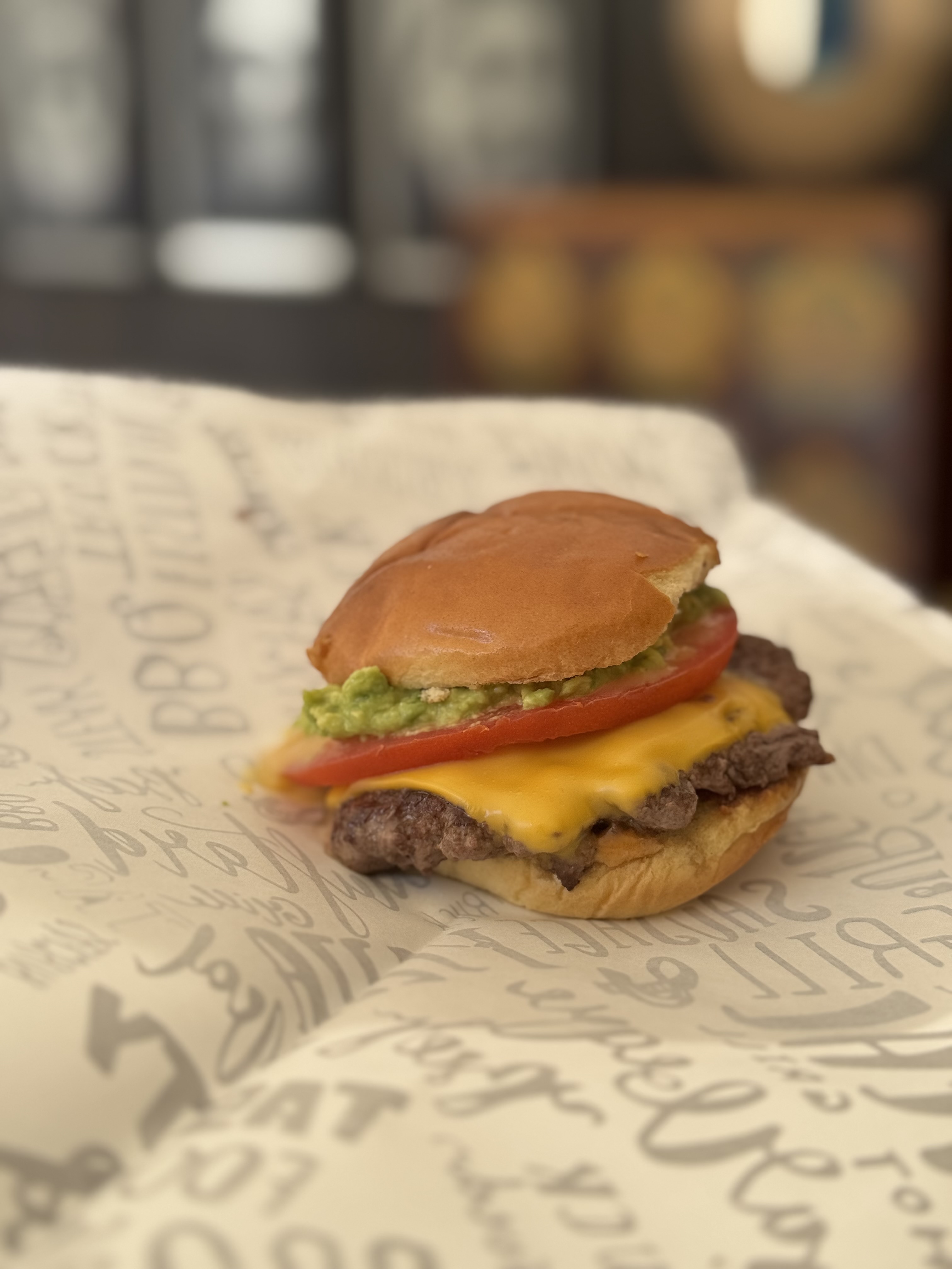 Hamburguesa smash con palta, tomate y queso sobre papel Plancha Brava